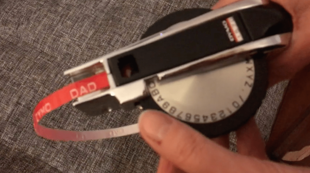 Hands typing DAD with a label maker